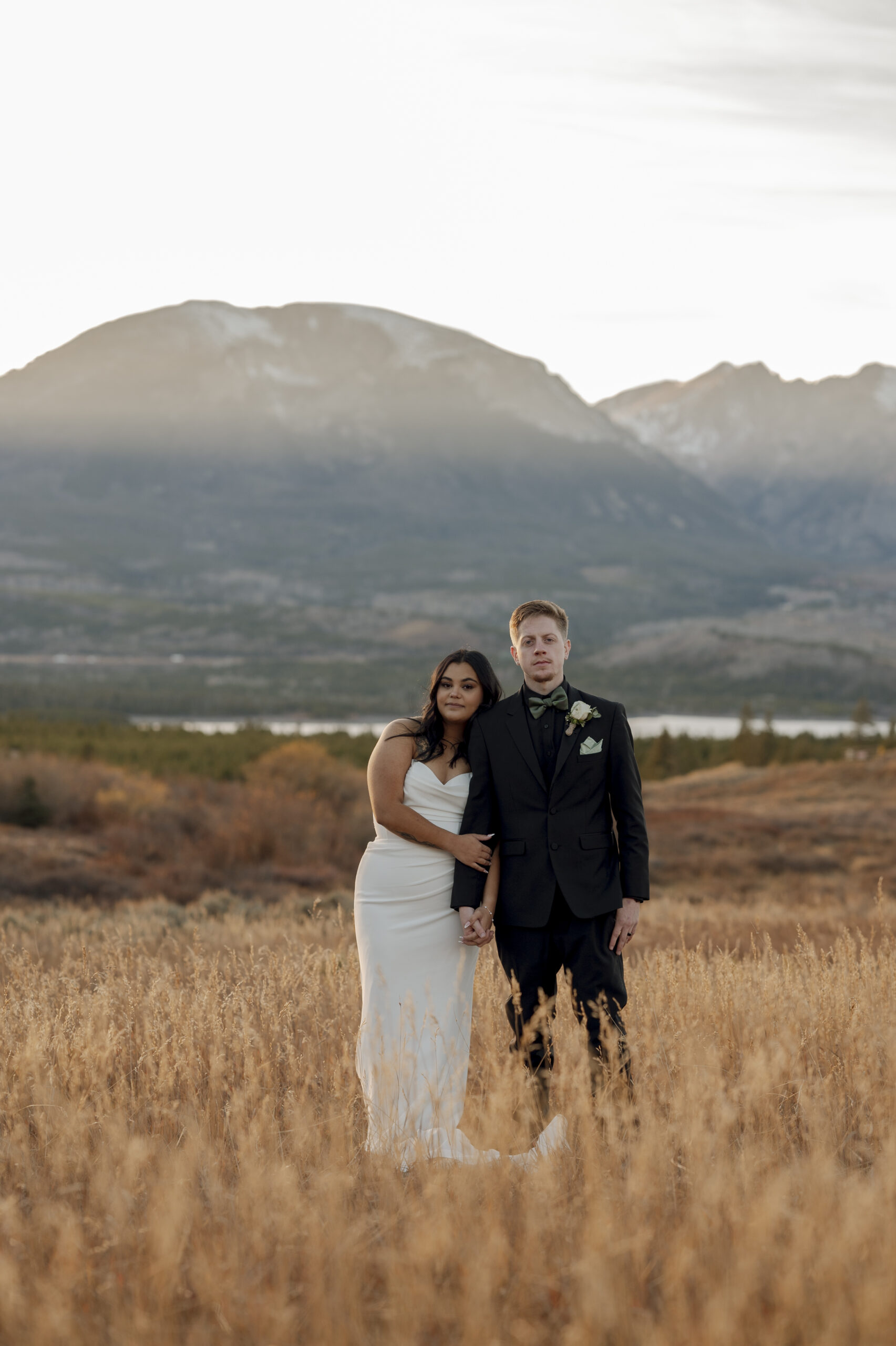 Elopement Photograph of couple in a field with mountains behind